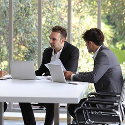 Three professionals in a well lit meeting room discussing documents