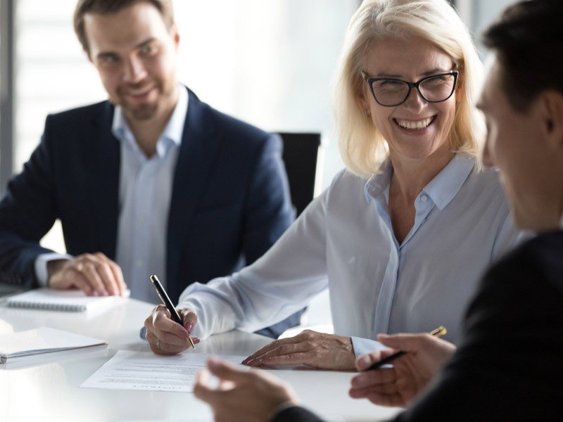 Three smiling professionals in a board room meeting