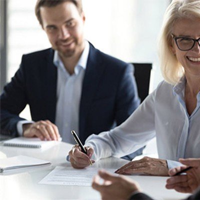 Three smiling professionals in a board room meeting